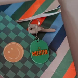 groene sleutelhanger met tekst meester in oranje